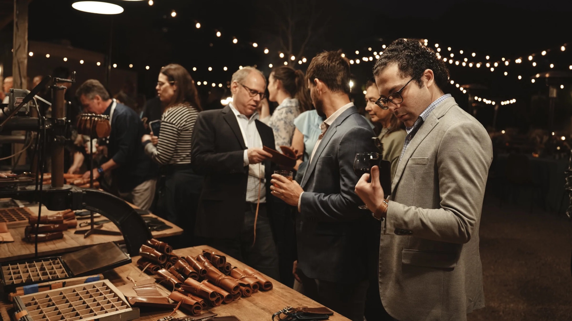 Guests browsing leather goods at a nighttime fire-branding event